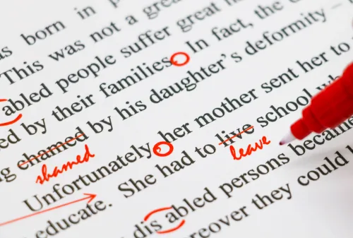 The editor is making red marks on the page to correct the writing, a skill they learnt in this editing course.