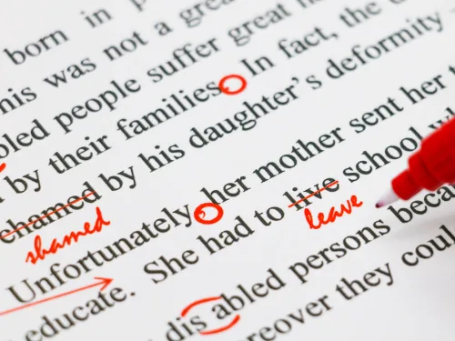 The editor is making red marks on the page to correct the writing, a skill they learnt in this editing course.